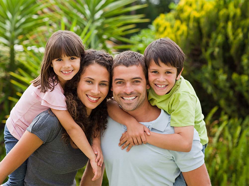 Happy family with smiling children outdoors, representing friendly, trusted pediatric dental care